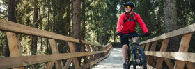 You ride a mountain bike on a wooden bridge built in the forest