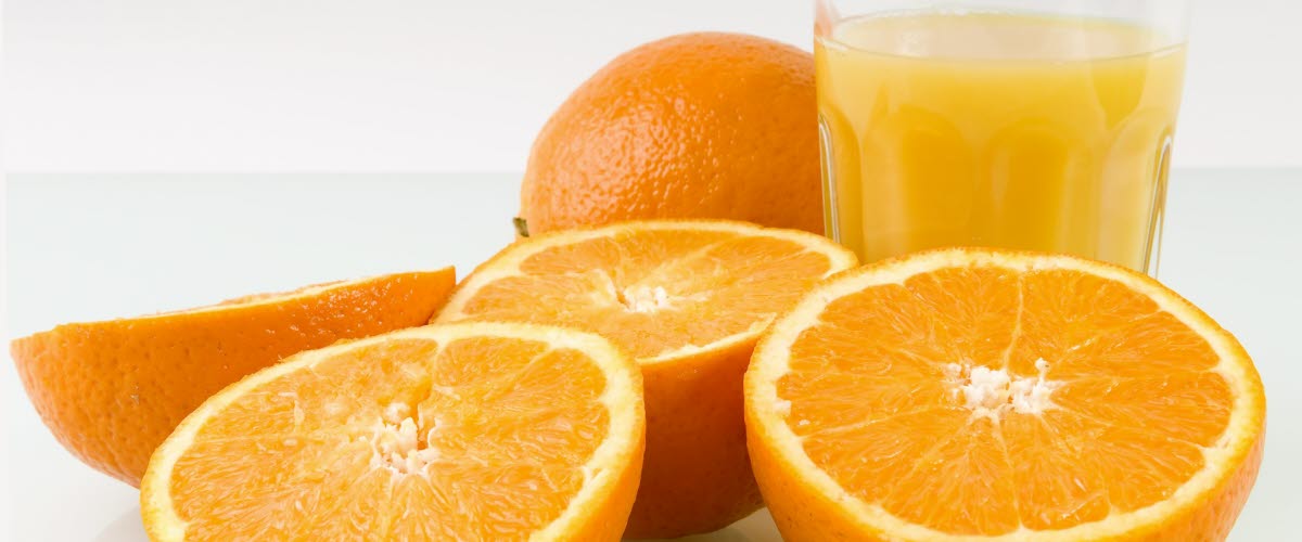 Gula apelsinhalvor med ett glas juice.