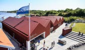 Building which houses the visitor centre Kosterhavet, In front of the entrance there are grass area and seating and the back is towards the sea.