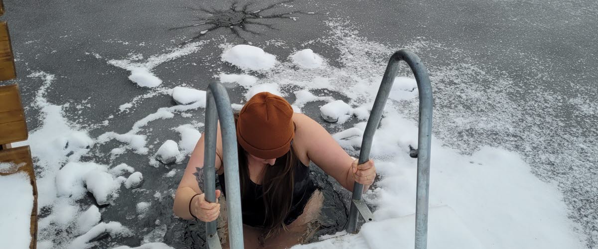 En person badar från en stege i en isvak.