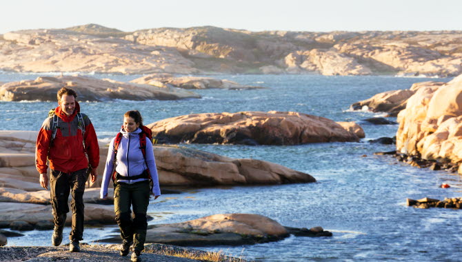 Par vandrar på klipporna med kobbar som bakgrund