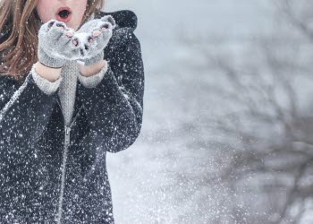Person blowing snow out of her hands