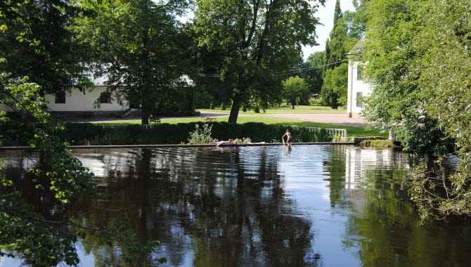 Two people taking a swim outdoors  next to a manor house.