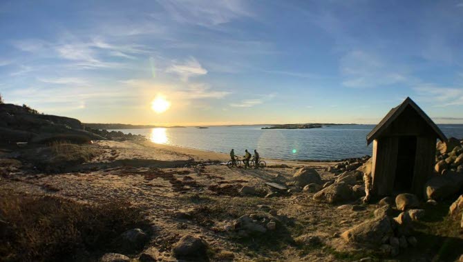Tre cyklister på en strand en solig eftermiddag.