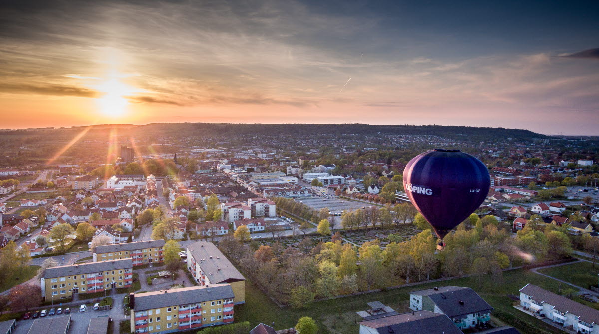 En svart luftballong med texten Falköping på flyger över staden.