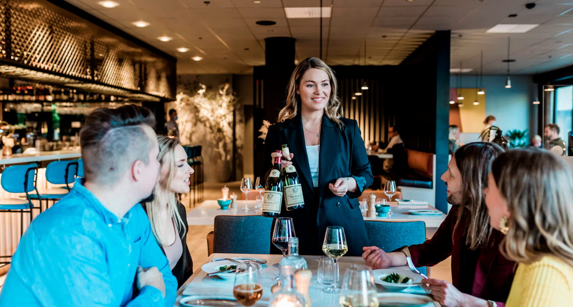 Leende servitris serverar vin vid bordet