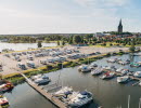 Flygbild över yttre hamnen i Mariestad, med husbilar på ställplatsen. Gamla Stan med domkyrkan i bakgrunden.