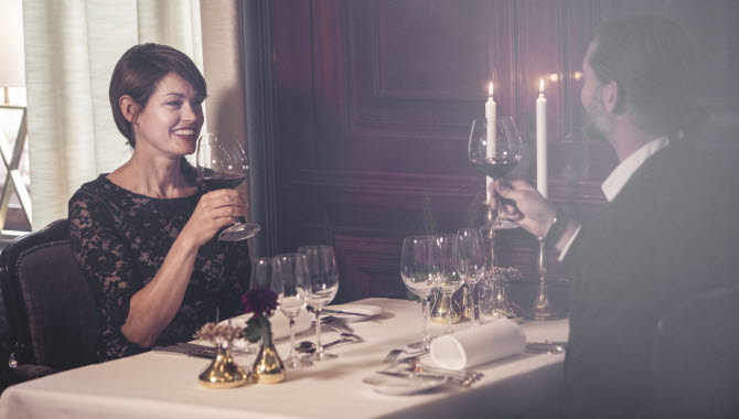 A woman and a man sitting at a table in a beautiful dining room. They toast