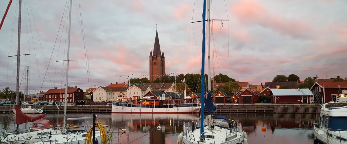 Skymning med enstaka båtar i hamnen i Mariestad med Gamla Stan och domkyrkan i bakgrunden.