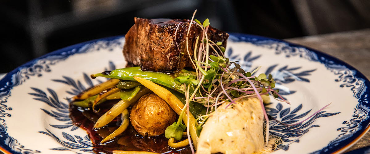 Tallrik med kötträtt och grönsaker på restaurang.