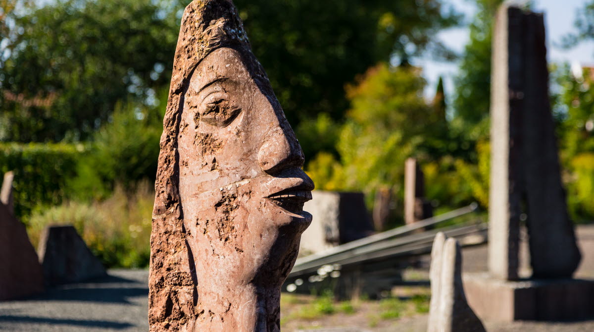 Skulptur i form av ett huvud med stor näsa och stor mun. 