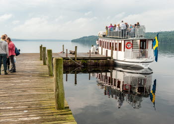 En båt ligger förtöjd vid en brygga där folk stigit ombord.