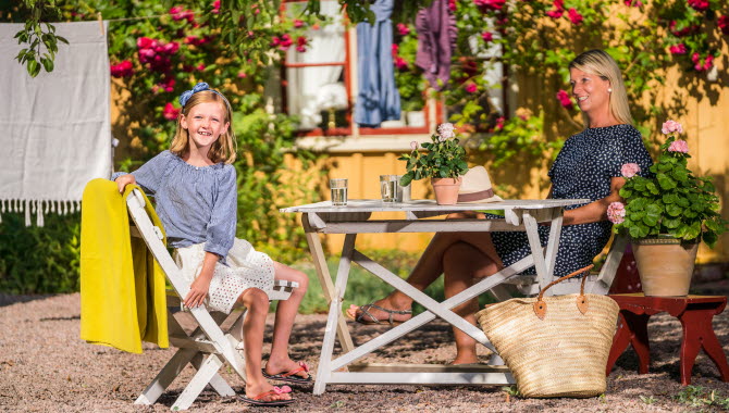 Mamma och dotter som sitter i Forsbergsgården trädgård i Hjo, ett privatboende mitt i de gamla stadsdelarna.