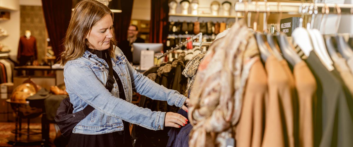 Woman peeking at clothes in a store.