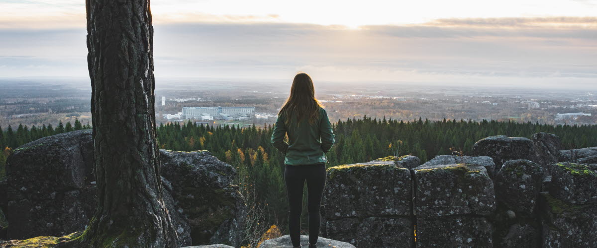 Kvinna tittar ut från ett berg över Platåbergens Geopark