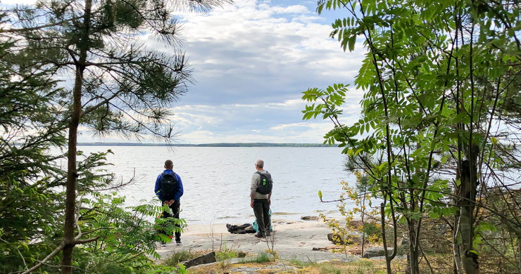 Three people at rocks by lake Vänern.