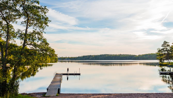 Utsikt över en brygga och en sjö med lätta moln och blå himmel.