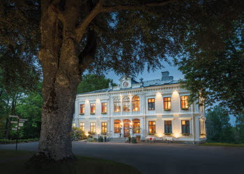 Stort vitt hus med ett träd framför.