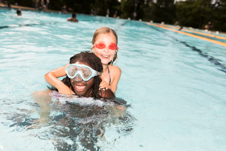 Two children playing in a outdoor pool.