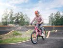 en tjej cyklar på en rosa cykel i en pumptrack