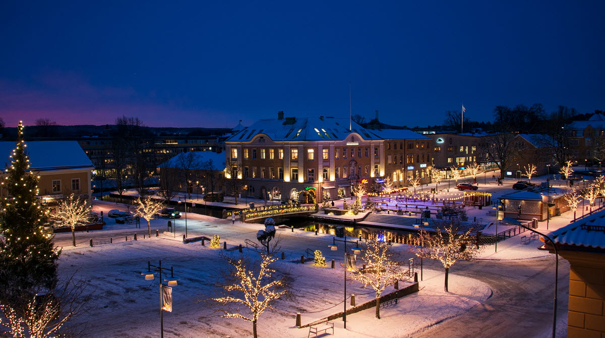 Stora torget och lilla torget i Alingsås med julbelysning. På stora torget syns julgranen och på lilla torget står isbanan, båda dekorerade med juleljus
