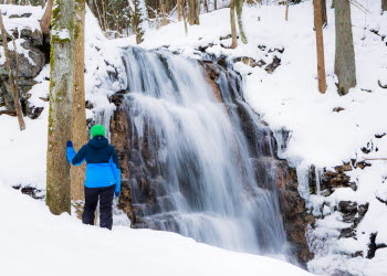 En person står framför Silverfallet, det är vintertid och fallet har frusit.