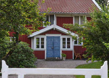 En närbild på en glasveranda med blåa dubbeldörrar som sitter på ett äldre rött hus.