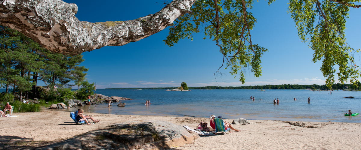 The sandy beach of Gardesanna by Lake Vänern, people sunbathing.
