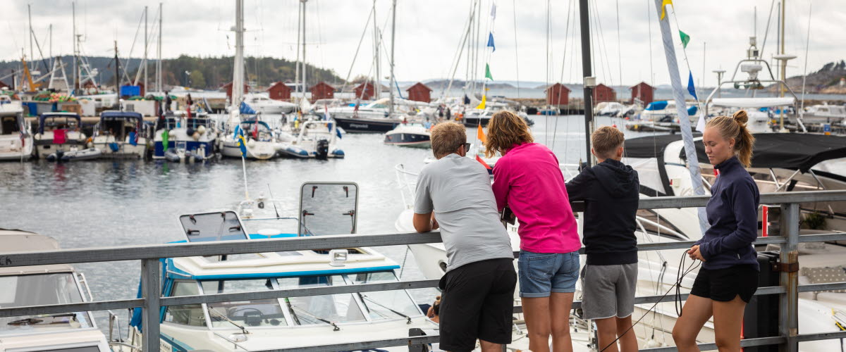Familj står på strandpromenaden i centrala Strömstad och tittar ut över gästhamnen. 