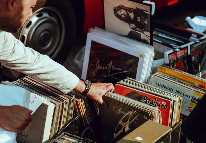 En närbild på en man som bläddrar bland massa gamla LP-skivor i en låda på golvet.