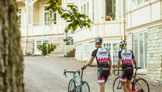 Kvinna och man som leder sina cyklar utan för Kurorten.
