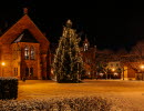 Ett torg med en stor julgran och ett äldre pampigt hus