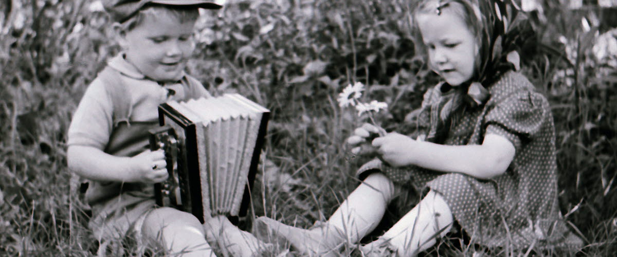 svartvit bild med två barn som leker i gräset