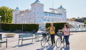 Två personer cyklar i en småstad.